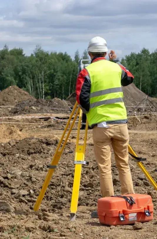 Opérateur topographe réalisant un levé à la station totale sur un terrain en cours de terrassement